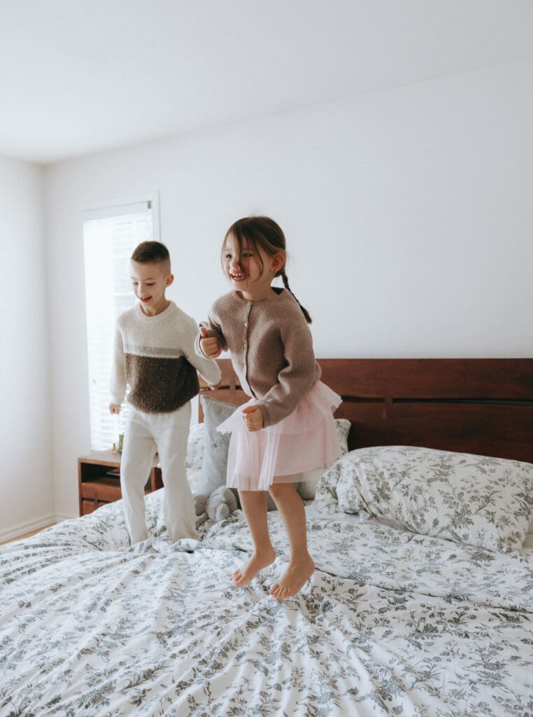 siblings jumping and playing on the bed for a candid photoshoot