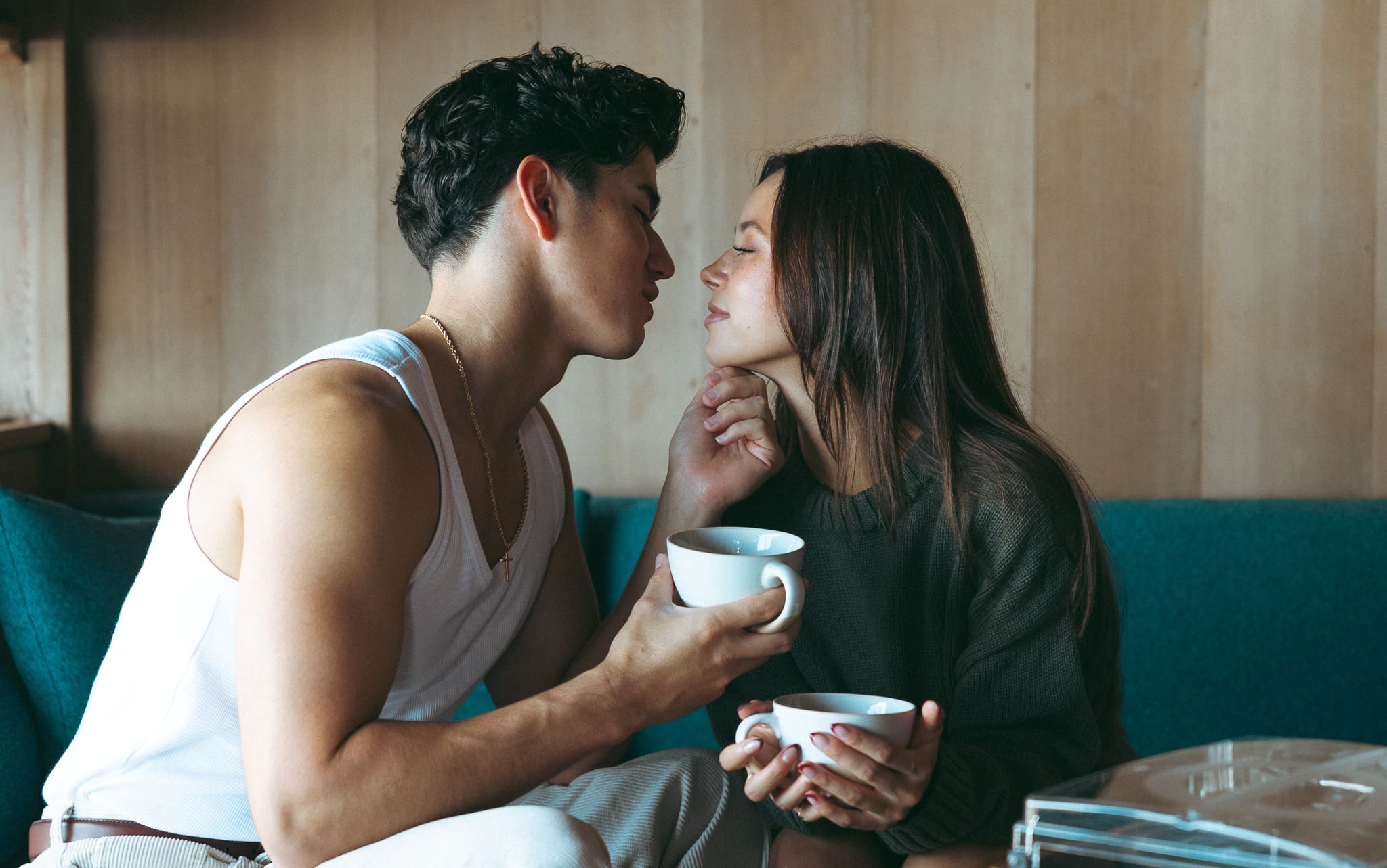 couple sharing coffee and leaning in for a kiss during an in-home couples photoshoot at a cottage