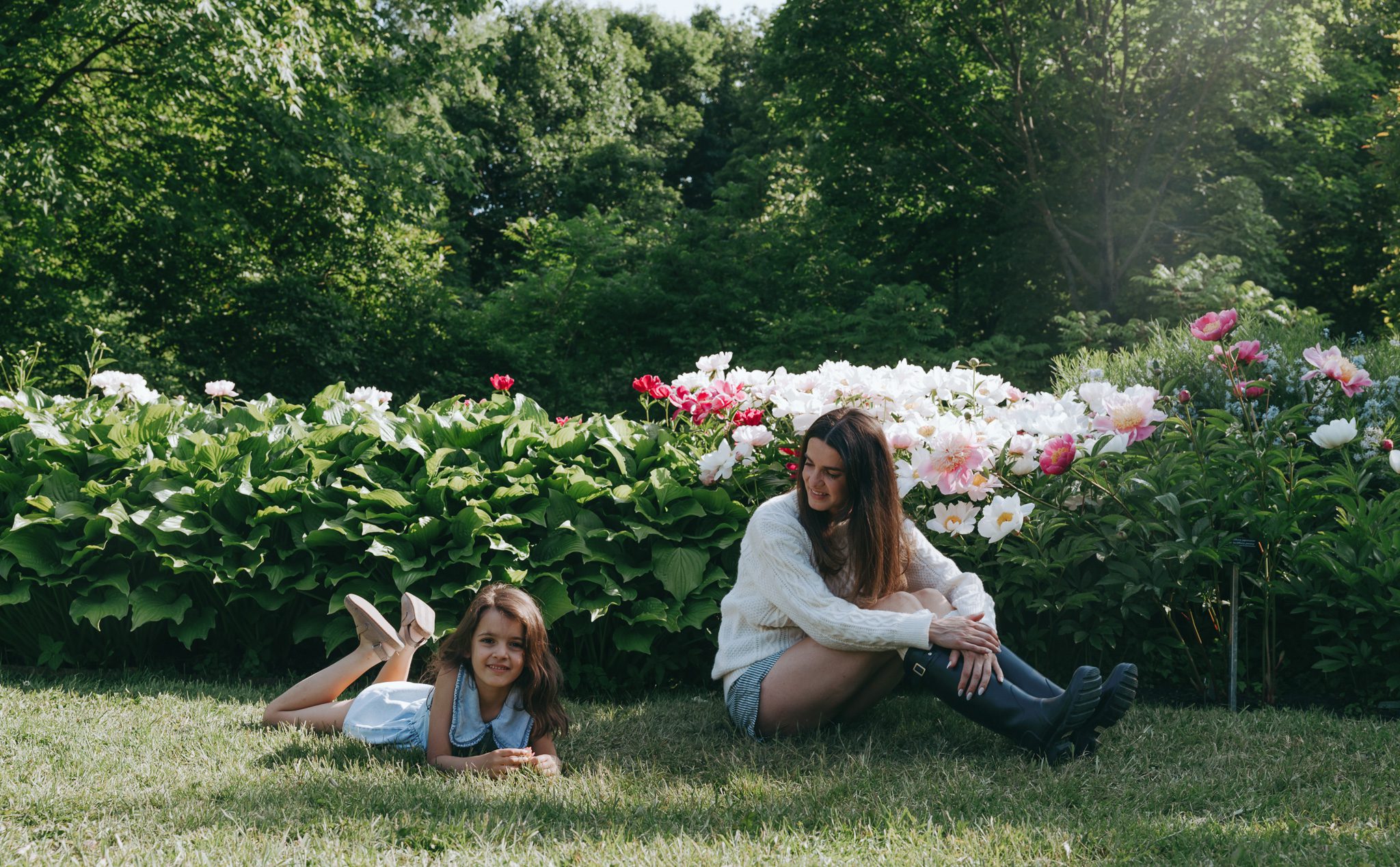 Mom and girl laying in the grass with flowers for a family photoshoot at the Jardin botanique de Montréal.
