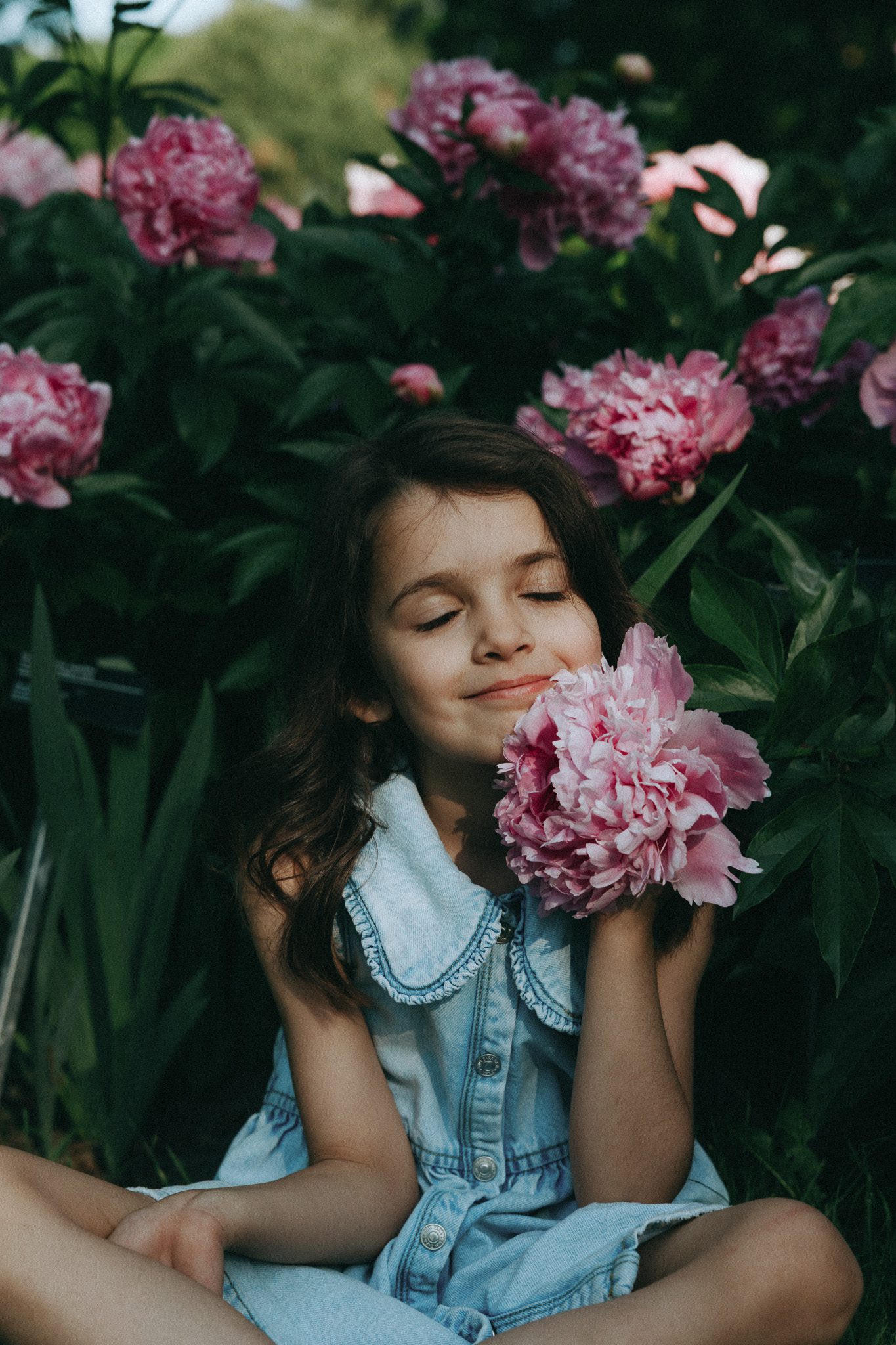Girl holding a flower near her face and smiling for a family session in Jardin botanique de Montréal