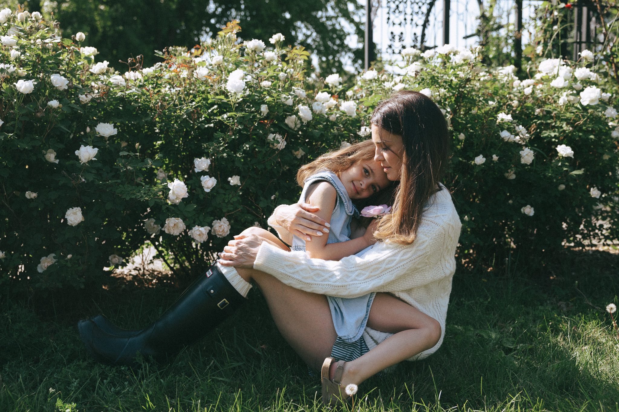 Mother and daughter hugging near a rose bush for a family photoshoot in Montreal