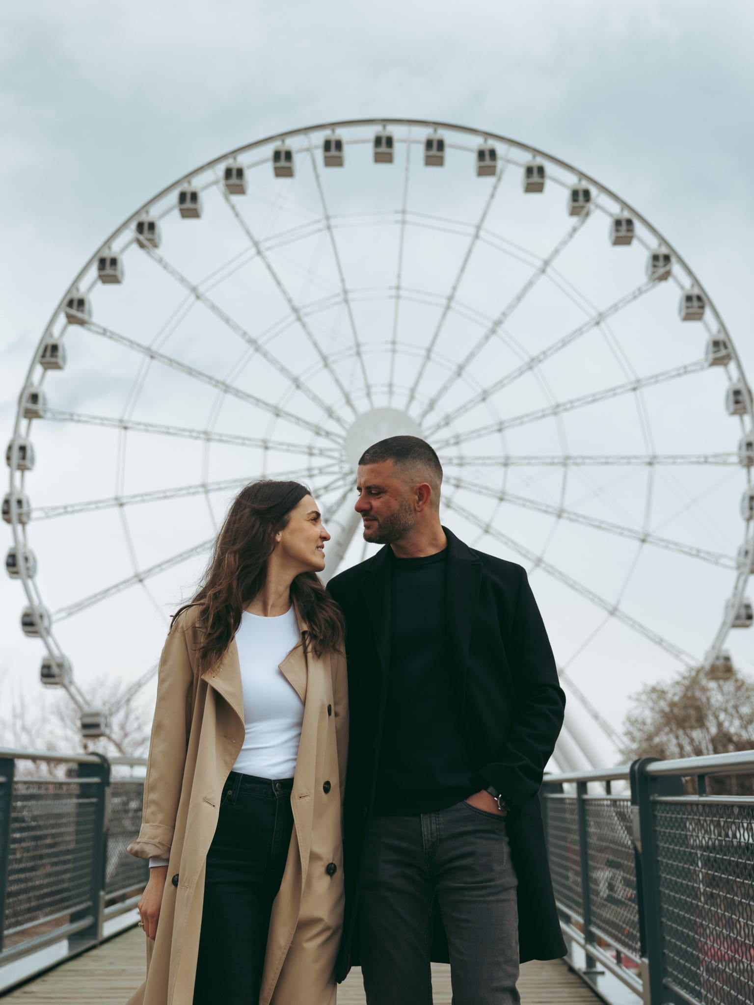 A couple standing at the La Grande Roue de Montréal for a couples photoshoot