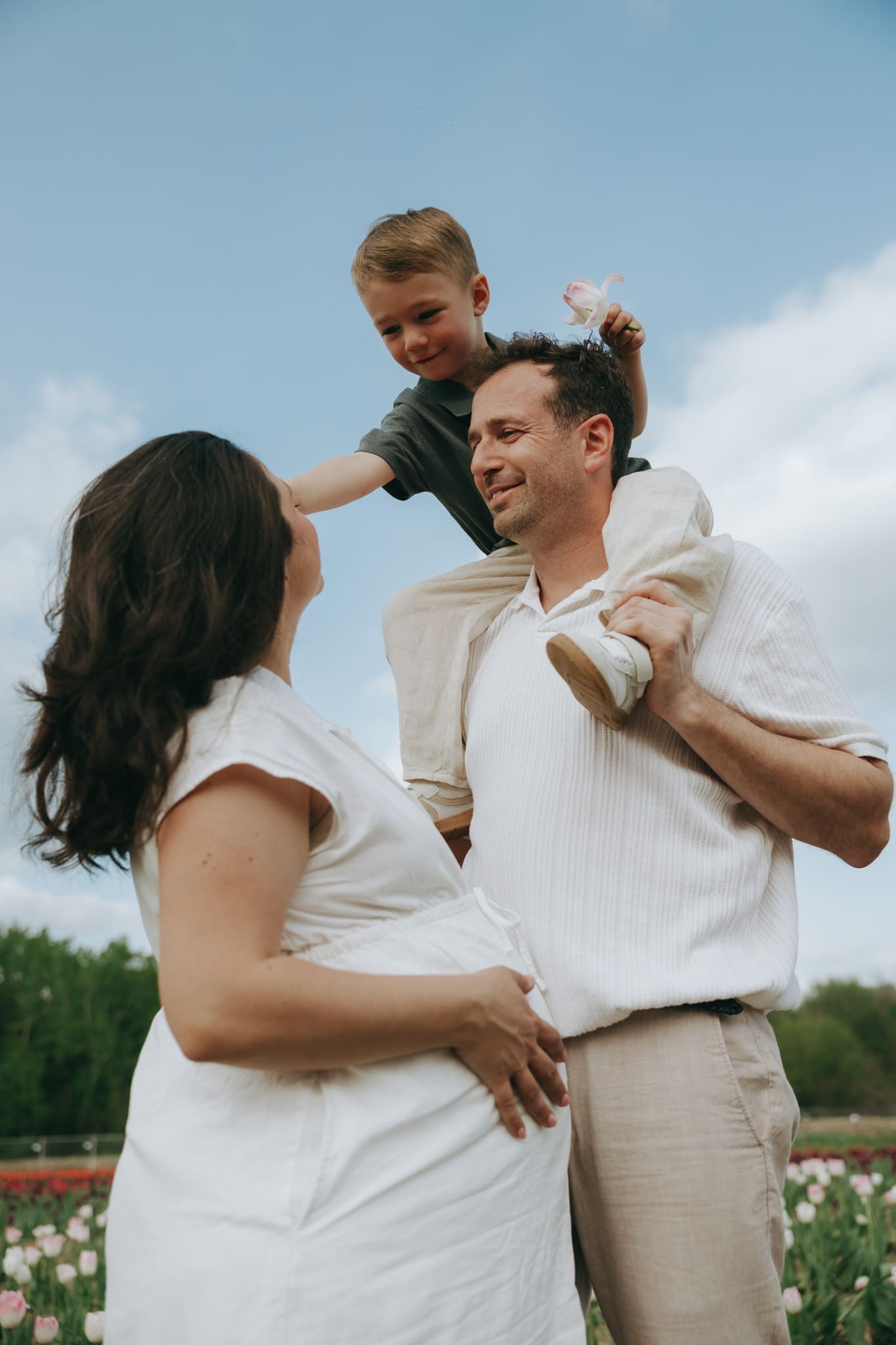 Son reaches for his mom while on dads shoulders for a family session at tulips.ca