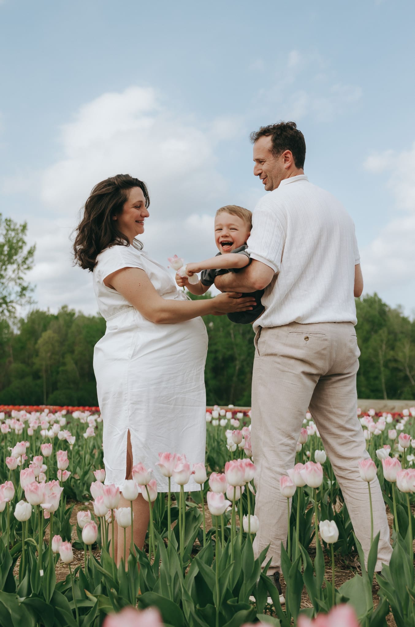 Mom and dad hold child and swing him up and down in the Montreal tulip field for a family session