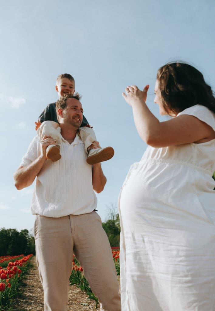 Dad holding son on his shoulders and looking at mom and her pregnant belly for a session in Montreal 